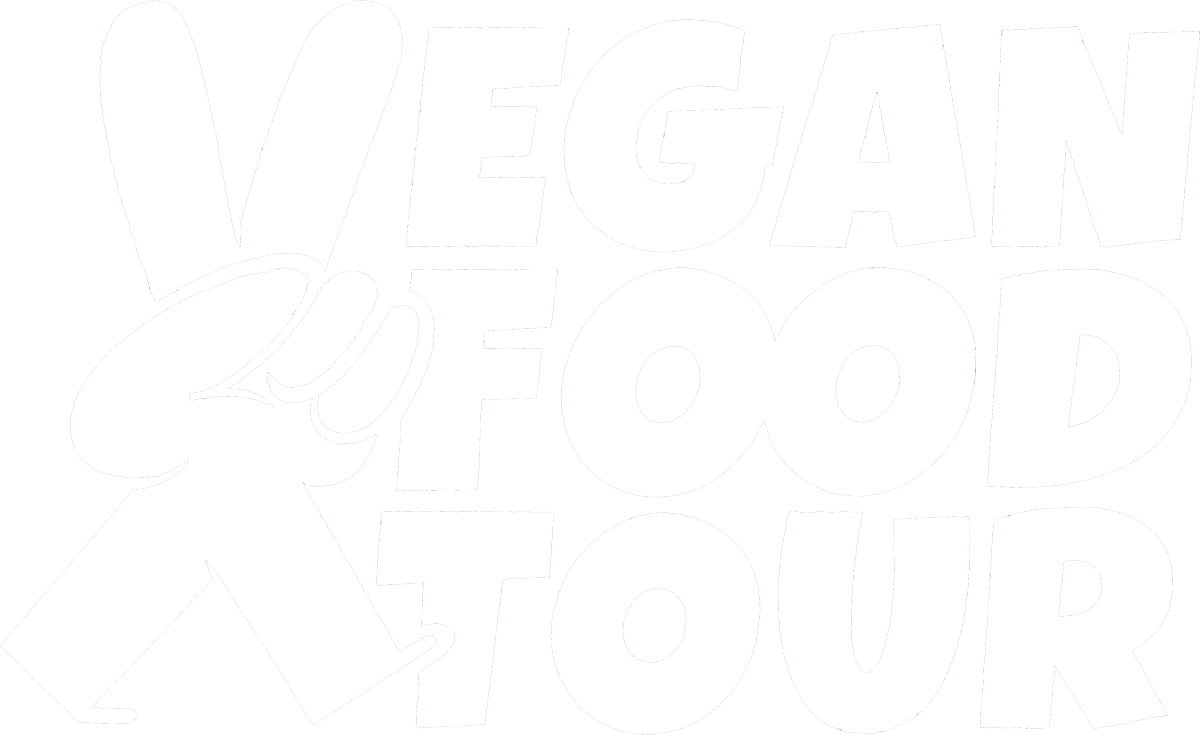 Het Vegan Food Tour Logo. Waarbij de V een wandeld handje is en de V wordt geïllustreerd door de wijs- en middel vinger. Ook wel het peace teken