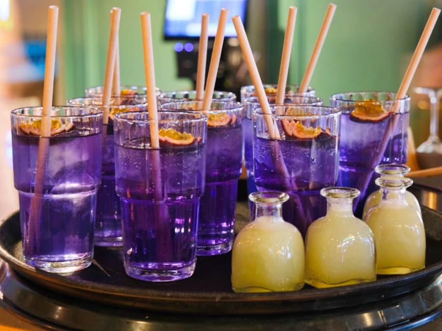 Een dienblad met donkerpaarse drankjes en een passievrucht