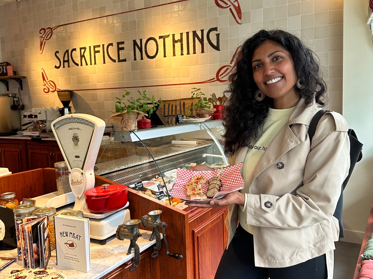 In een vegan slagerij zie je iemand die en bordje vasthoudt met daarop een aantal veganistische vleesproducten