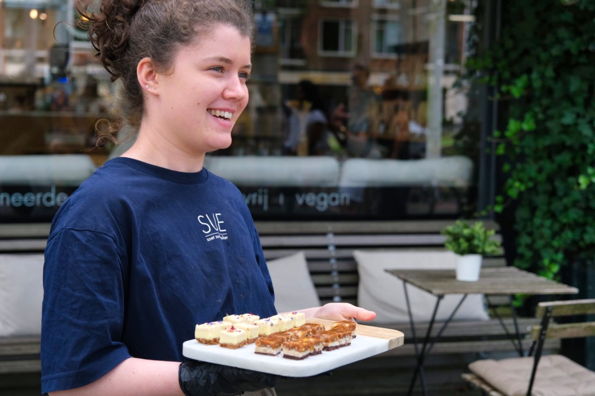 Iemand in een blauw shirt houdt een plankje vast met daarop allemaal kleine bites