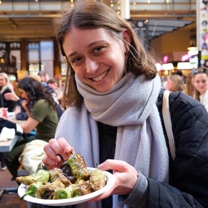 Iemand met een bord met padron pepers in de foodhall in Amsterdam