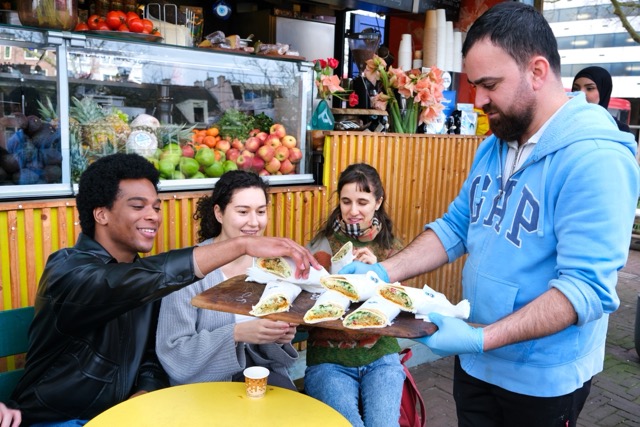 Iemand deelt falafel uit aan mensen die meedoen met een teamuitje in Amsterdam