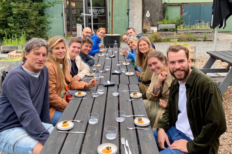 Groep mensen zit aan een lange tafel met eten voor zich tijdens een teamuitje in Utrecht.