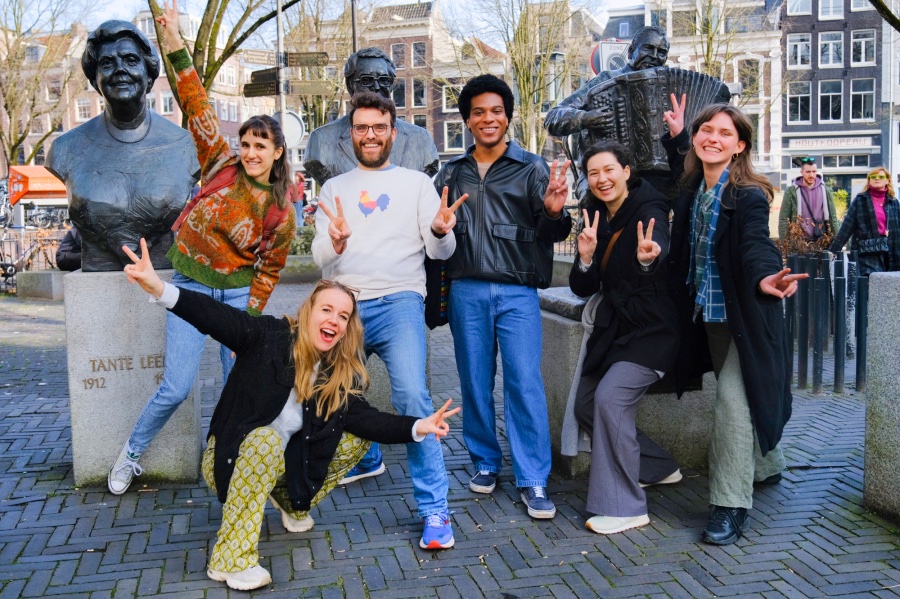 Een groep deelnemers aan een teamuitje in Amsterdam poseert voor standbeelden op een plein in Amsterdam.