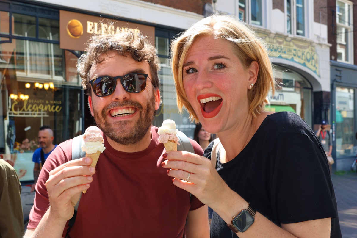 Een man en vrouw lachen in de camera met een ijsje tijdens de street food tour in Den Haag.