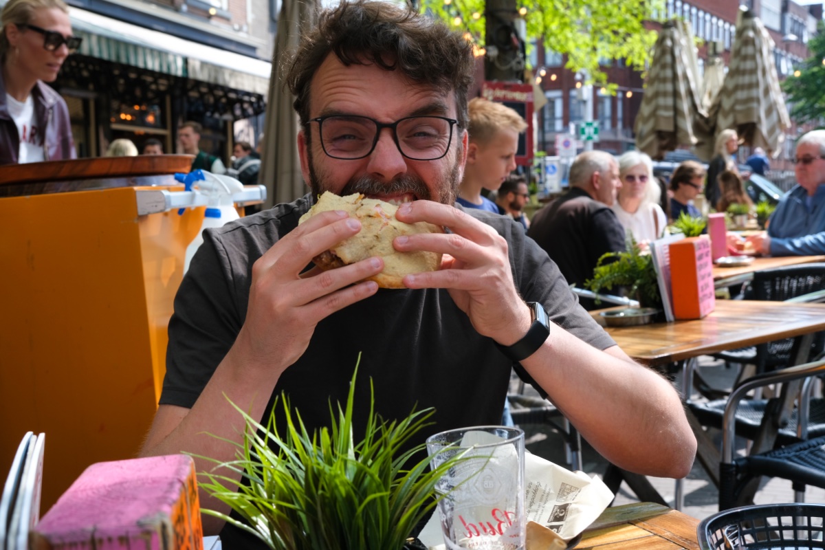 Man eet een pita tijdens een vegan food tour en zit aan tafel aan de Grote Markt in Den Haag.